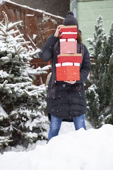 woman returning home from shopping holding pile of christmas present boxes 