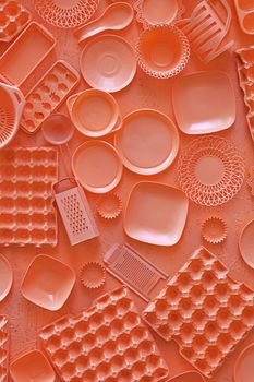 Close up flat lay of different orange color painted kitchen utensils and tools, grater, spoon, egg carton, plastic disposable plates, elevated top view, directly above