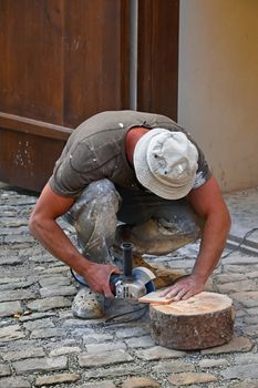 Close up of working man cutting and shaping ceramic tile with angle grinder