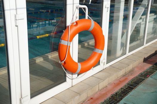 Orange lifebuoy on a wall of a protection of the swimming pool