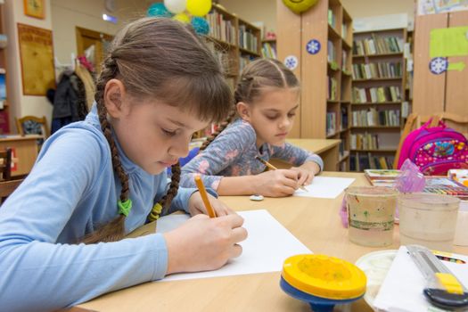 Schoolgirls in extracurricular activities draw in the library