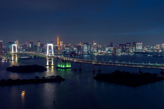 View of Tokyo cityscape and Rainbow bridge at night in Japan.