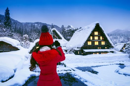Young woman taking a photo at Shirakawa-go village in winter, UNESCO world heritage sites, Japan.