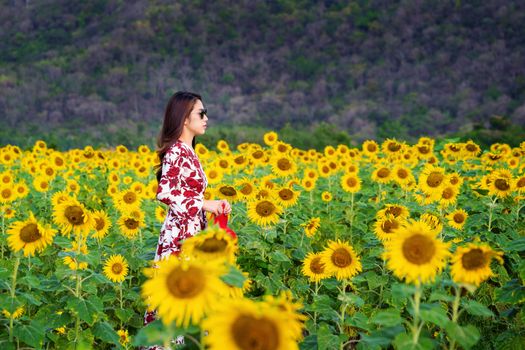 Young woman standing in a field of sunflowers.