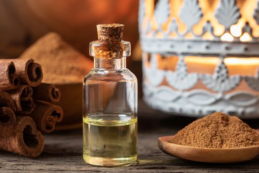 A bottle of essential oil with cinnamon sticks and powder