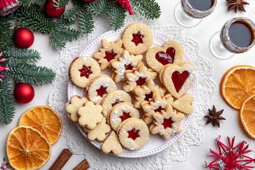 Traditional Linzer Christmas cookies filled with strawberry jam arranged on a plate, top view