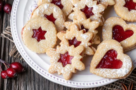Traditional Linzer Christmas cookies filled with strawberry jam on a rustic background