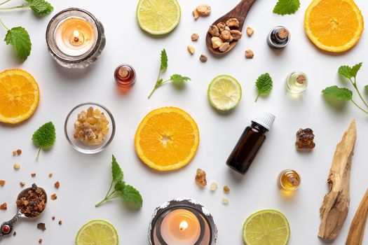 Bottles of essential oil with fresh citrus fruit, melissa, myrrh, white sandalwood and other ingredients