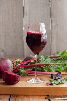 Red beet juice in a glass with fresh root and leaves