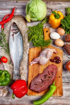 Chicken, fish and vegetables on an old wooden desk