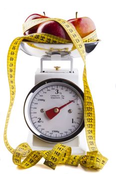 Red apple with  yellow measuring tape on kitchen scale isolated on white