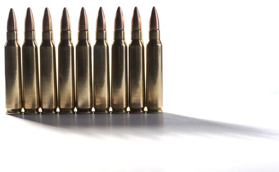 Row of shiny rifle bullets standing together isolated on white with shadows