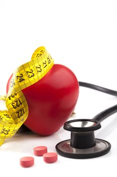 Red heart with stethoscope yellow measuring and red pills isolated on white background