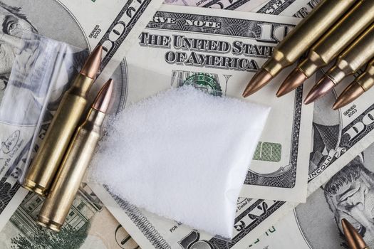 Bullets on dollar banknotes with a bag of white drug powder