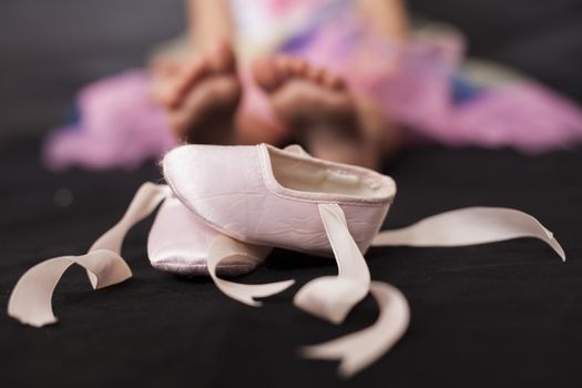Pink ballerina baby shoes with girl feet in the background