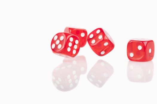 Four red bouncing dice isolated on white background with reflection