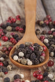 Various type of peppers on wood spoon and old wood table close-up