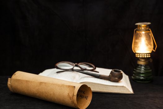 Old scrool with bible glases and a pipe in fire lamp light