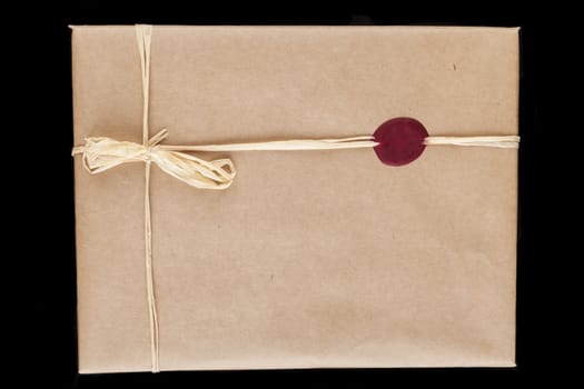Old brown wrapping paper gift close-up with tied bow and red wax seal