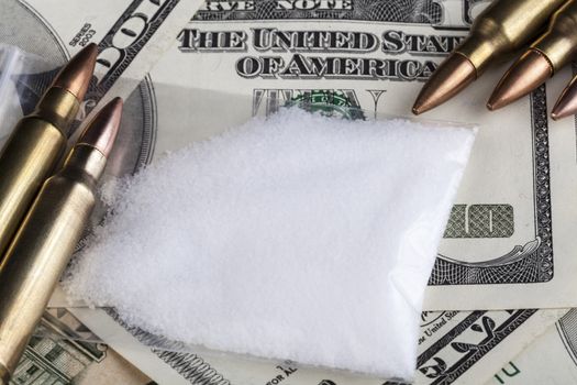 Bullets on dollar banknotes with a bag of white drug powder