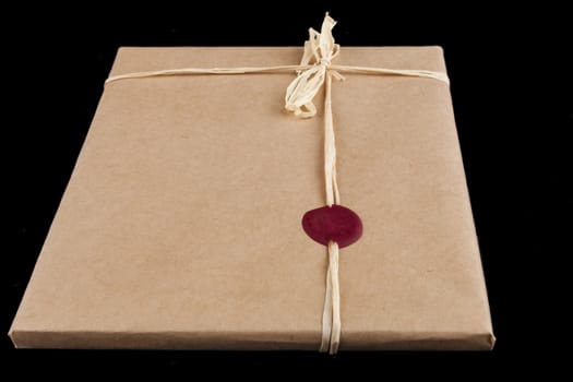 Old brown wrapping paper gift close-up with tied bow and red wax seal