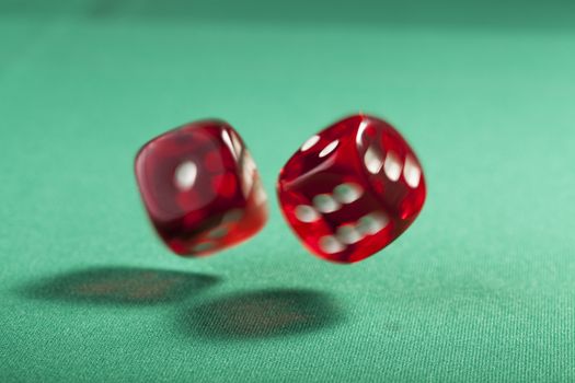 Pair of bouncing red dice blured on green  background 