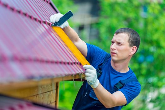 Professional with the tool repairs the roof of a residential house