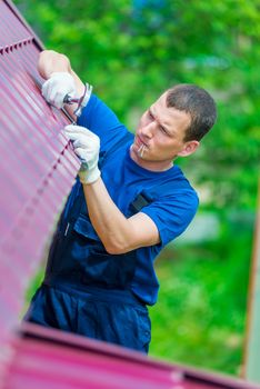 The man is an experienced worker repairing the roof of a residential private house in the fresh air