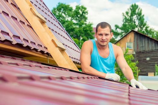 Portrait of a man with a toolbox on the roof of the house during the repair