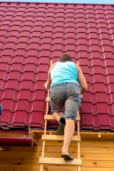 view from the back repairman on the stairs against the background of the roof of the house