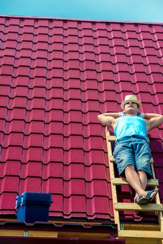 A worker takes a sun bath on the roof of the house during a break