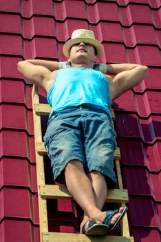 A worker takes a sun bath on the roof of the house during a break