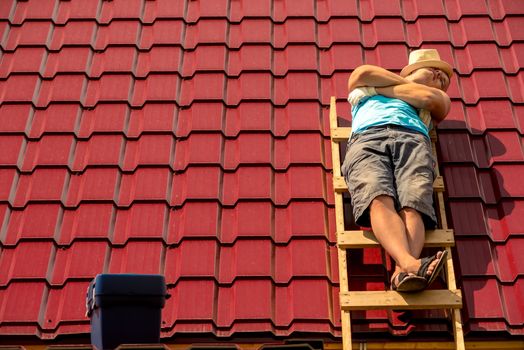 a worker asleep during a break sunbathing on the stairs on the roof of a house
