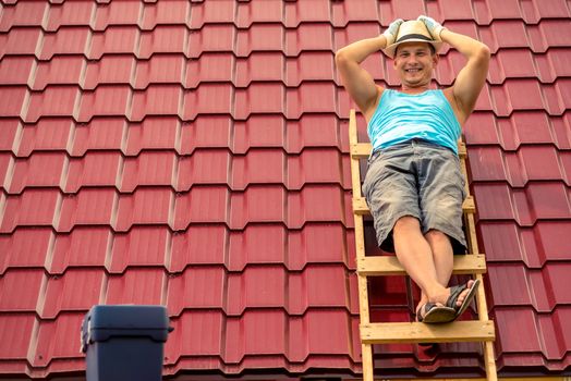 Happy man posing on the stairs against the background of the roof of the house, making repairs cover