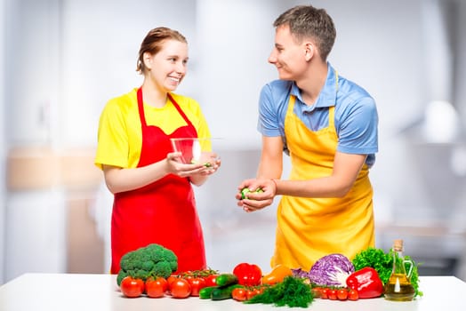 man and woman preparing healthy vegetable salad in the kitchen