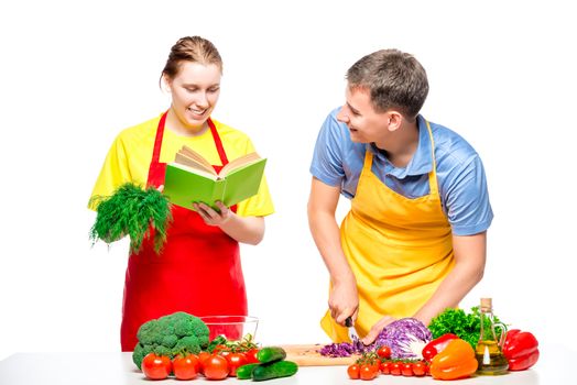 woman with a recipe book, a man cuts vegetables cooked together a salad on a white background