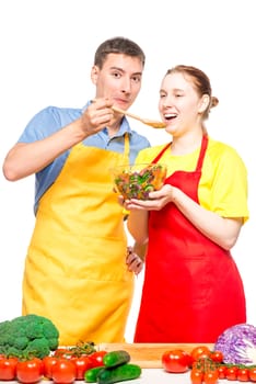a man with a wooden spoon feeds a girl with a useful vegetable salad on a white background