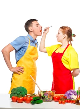 woman with a wooden spoon feeds a man a useful vegetable salad on a white background