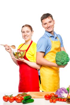 vertical portrait of a happy couple with vegetables and salad on white background