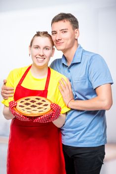 housewife in apron with a pie and her beloved husband, portrait in the kitchen