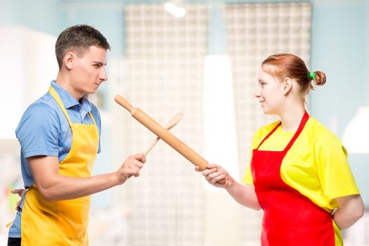 man and woman in an apron with kitchen utensils fighting in the kitchen