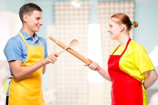 portrait of a man and a woman in an apron with kitchen utensils fighting in the kitchen
