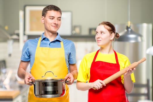 horizontal portrait of a man with a pan and a woman with a rolling pin in the kitchen