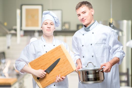 professional cooks with kitchen utensils in the kitchen of the restaurant