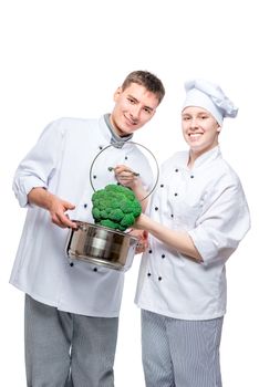 vertical portrait of fellow chefs with pan and broccoli on white background