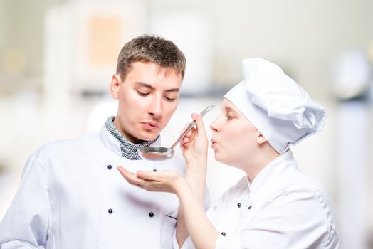 professional chefs try soup from a ladle on the background of the kitchen