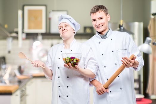 emotional young professional chefs with a dish on the background of the kitchen