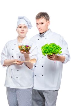 young cooks in suits with salad in hands on white background