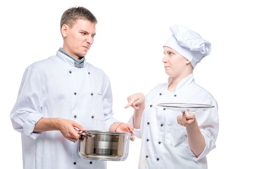 chef looks at a cooked dish of a young cook with a reproach on a white background