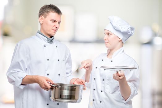 chef looks at a cooked dish of a young cook with reproach in the kitchen